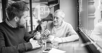 To menn som sitter på café og drikker kaffe ved vinduet