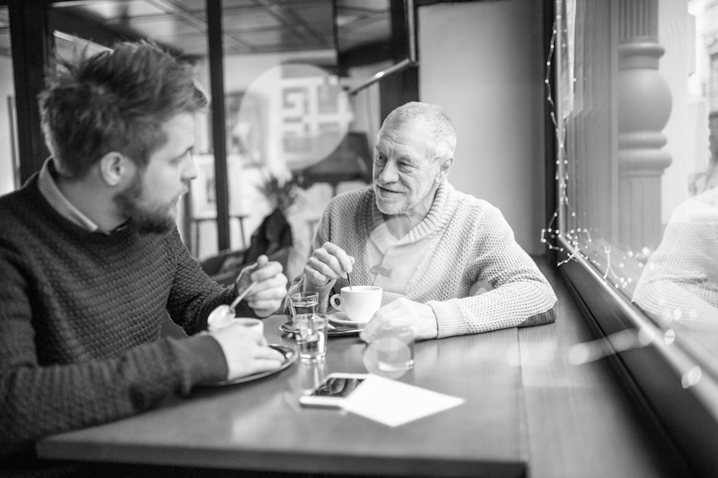 To menn som sitter på café og drikker kaffe ved vinduet
